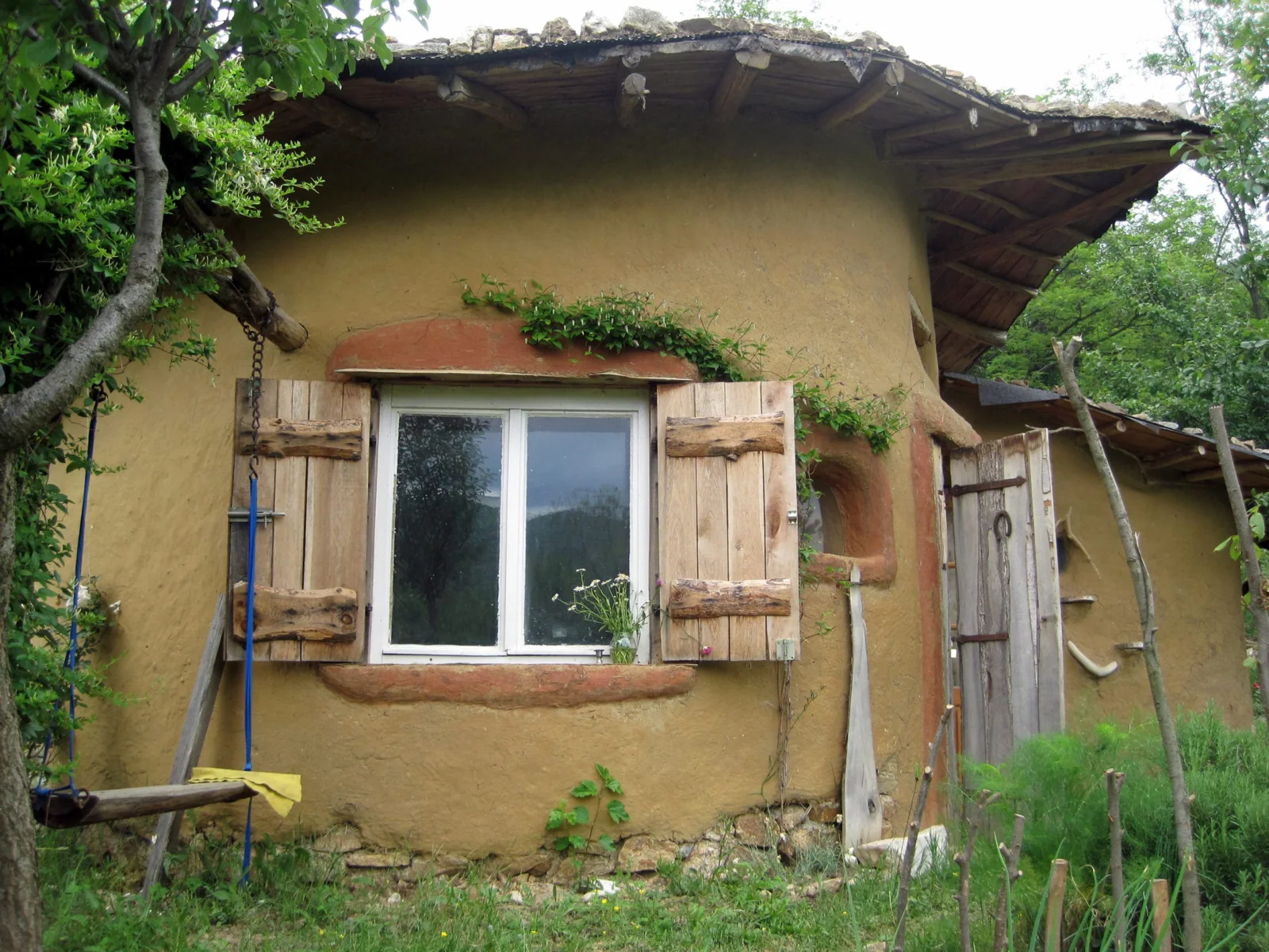 Fațada din pământ, obloanele de lemn și acoperișul vegetal ale Casei Verzi